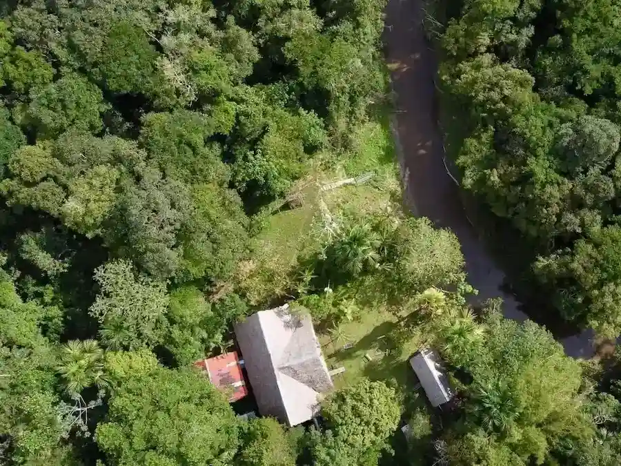Aerial view of La Luna del Amazonas retreat center surrounded by dense Amazon rainforest, with a main building and nearby river.