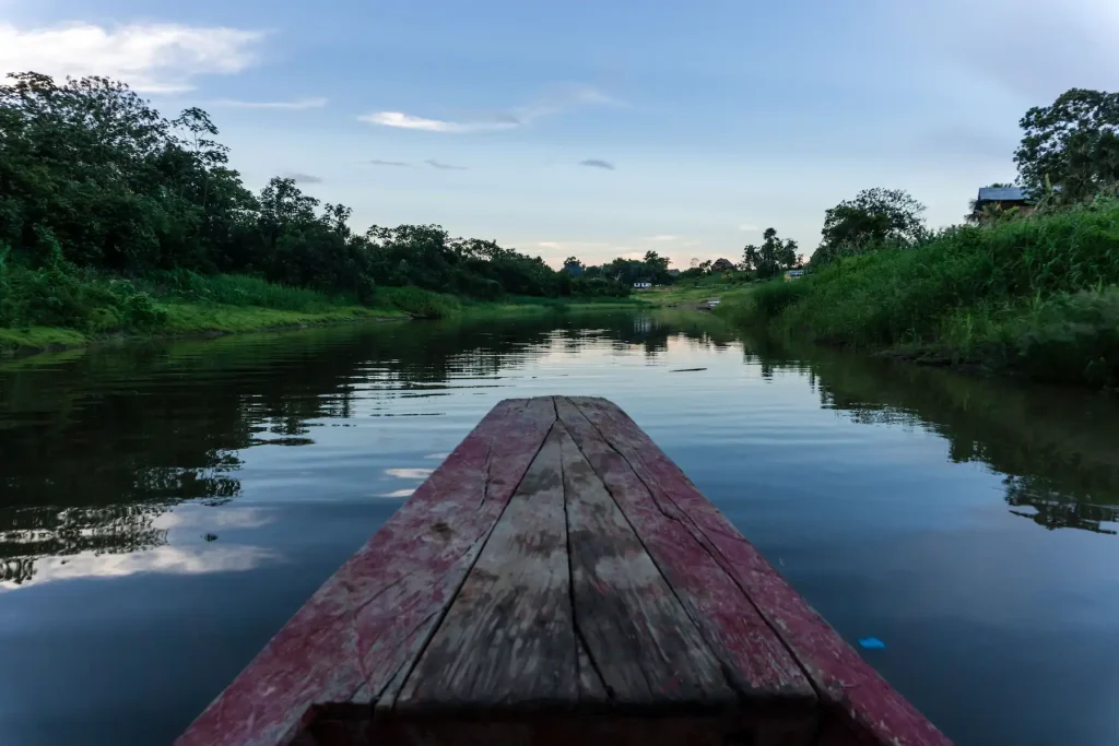 View from the bow of a traditional wooden boat traveling down the Amazon river toward La Luna del Amazonas
